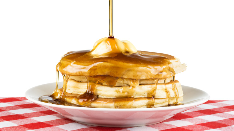 Maple syrup being poured over pancakes