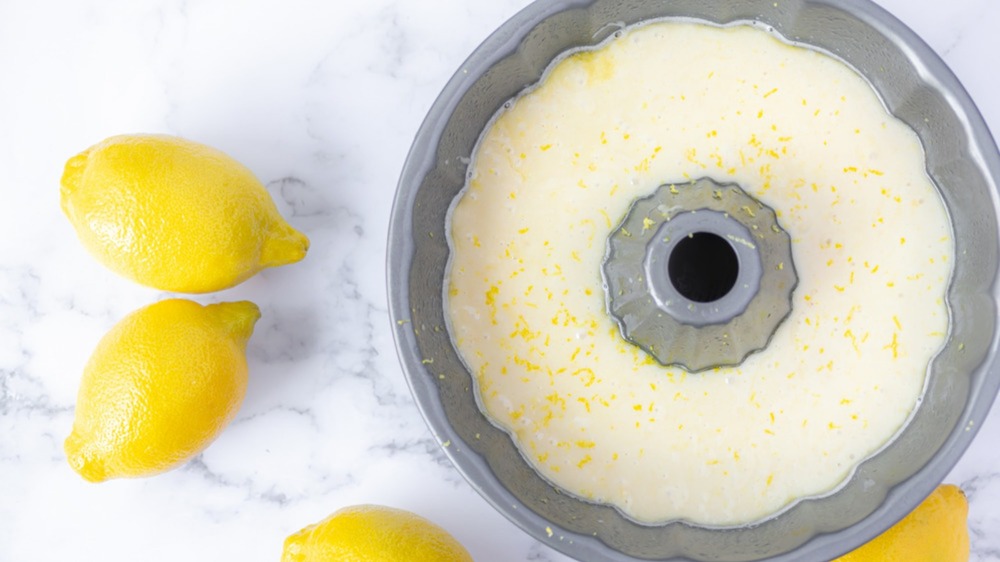 lemon cake batter in a bundt pan surrounded by fresh lemons