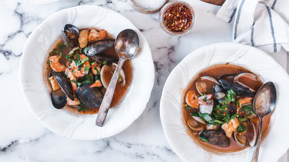 Cioppino seafood stew soup in white bowls with metal spoons