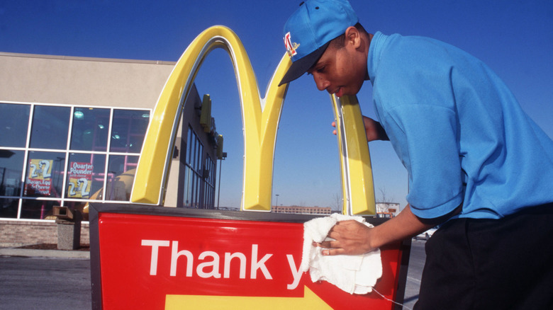 A McDonald's employee cleaning an exterior sign