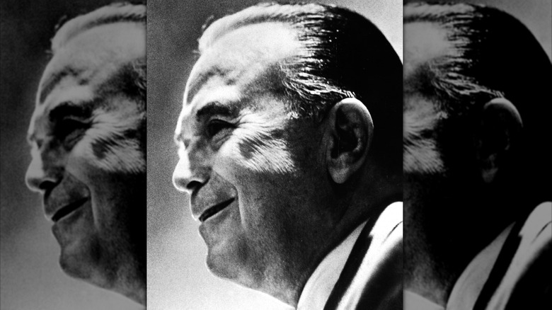 A black and white photograph of Ray Kroc smiling in profile