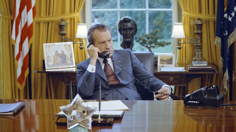President Richard Nixon at his desk in the Oval Office, listening on the phone