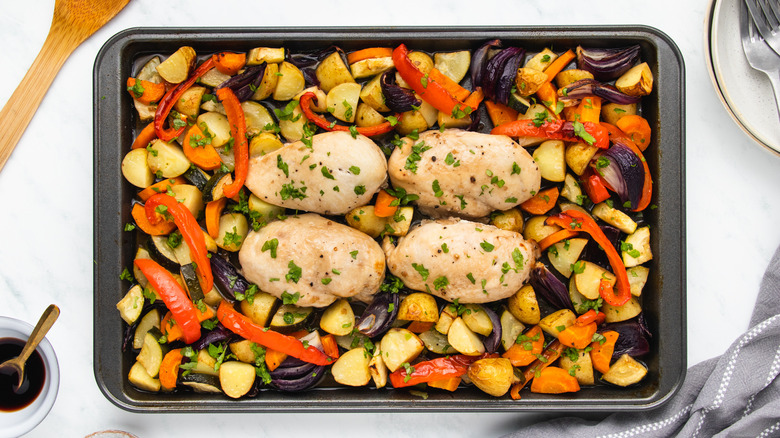 Roasted chicken breasts and vegetables on baking sheet