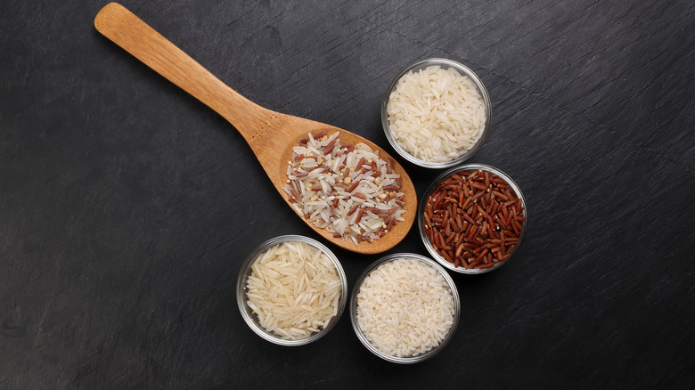 Spoon and metal bowls with different rice varieties