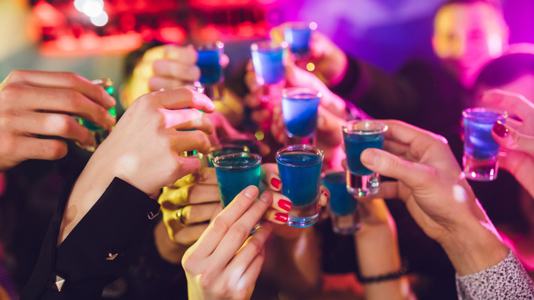 Group of friends cheers shot glasses