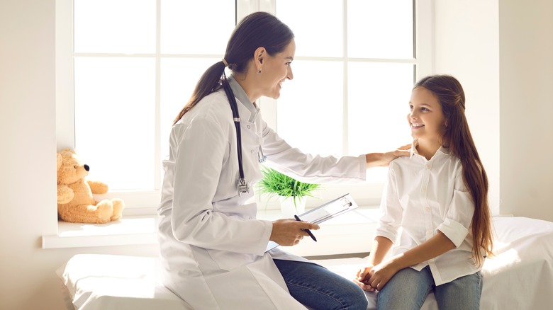 female pediatrician smiling at a girl during an exam