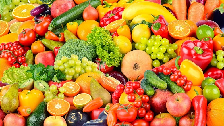 pile of fresh fruits and vegetables with tomato, apples, oranges, kale