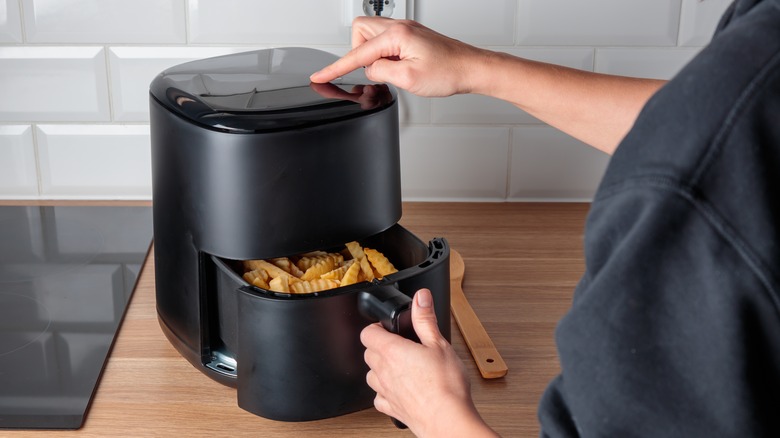 Person removing french fries from air fryer