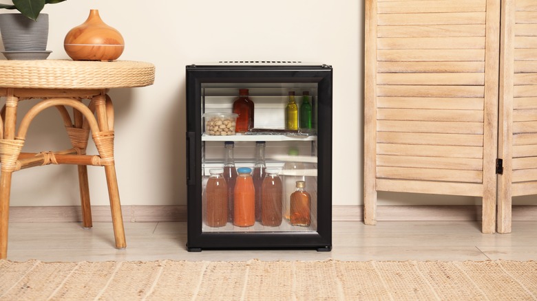 Small black beverage cooler in living space next to rug and wicker table
