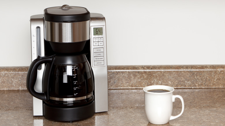 Drip coffeemaker on kitchen counter with white mug