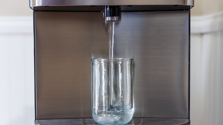 Dispenser pouring water into clear glass