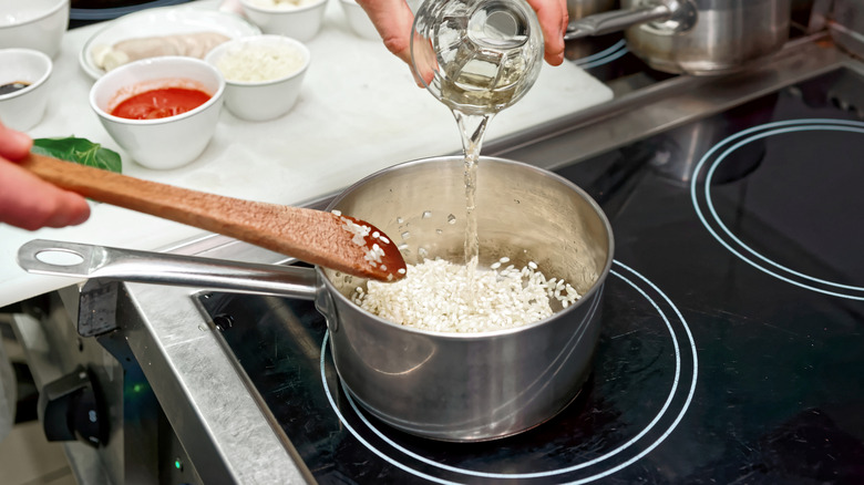 Chef adding white wine to risotto.