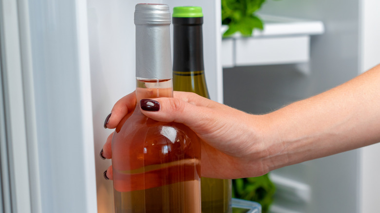 Hand on bottle of wine in refrigerator
