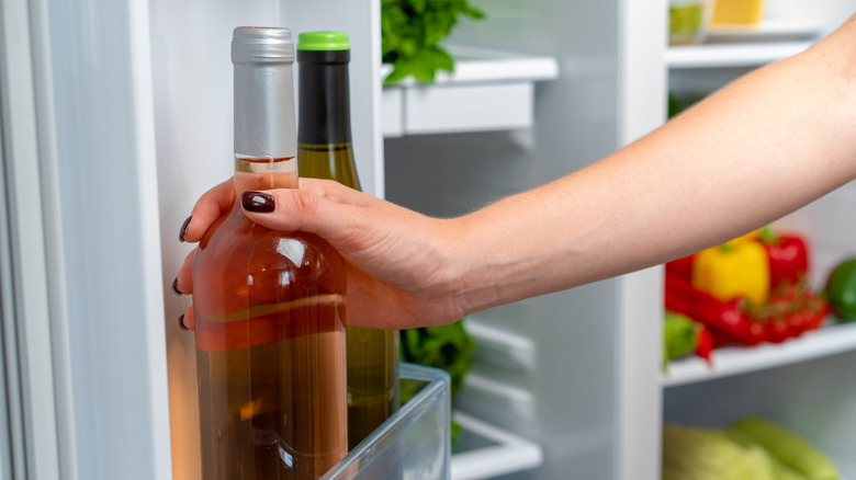 Hand on bottle of wine in refrigerator