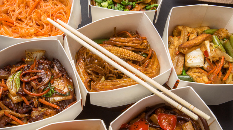 Pair of wooden chopsticks perched atop several boxes of takeout
