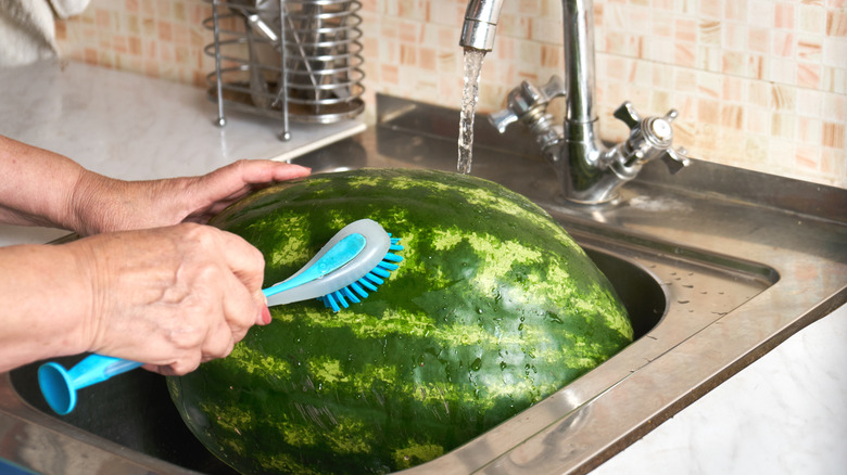Someone scrubbing watermelon in a sink.