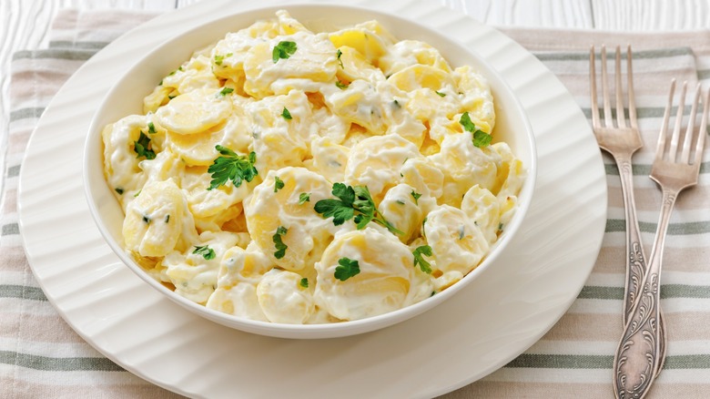 A bowl of classic potato salad next to two forks.