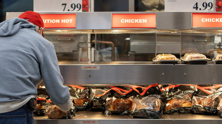Customer selecting rotisserie chicken from case