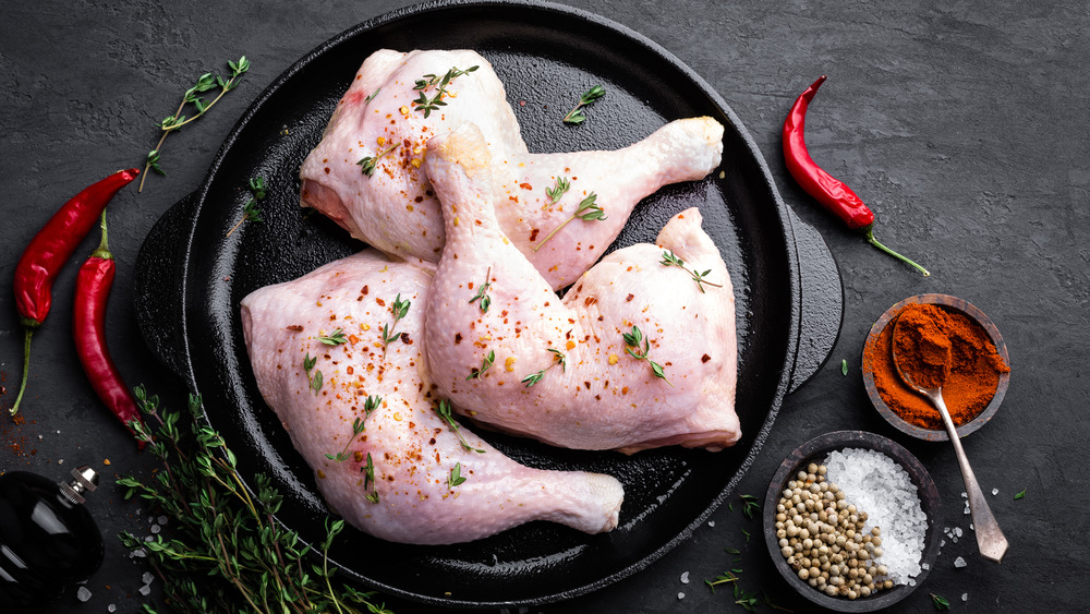 Raw chicken legs in pan with peppers and spices