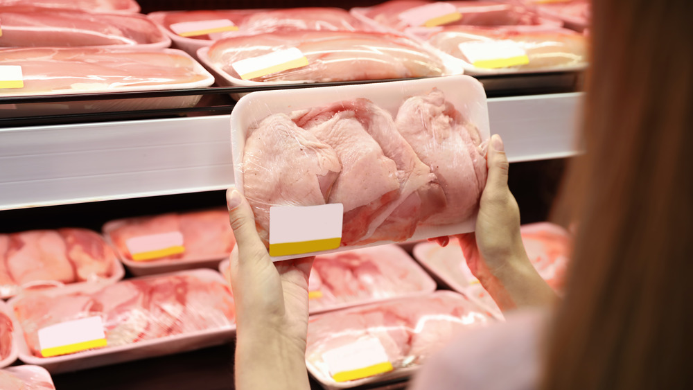 Woman choosing chicken in grocery store