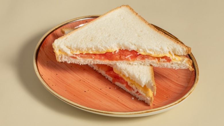 Cheese and tomato sandwich on white bread, cut diagonally and stacked on a plate