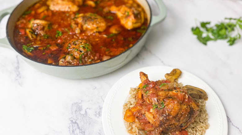 chicken cacciatore in a pan and plated in white dish on bottom right