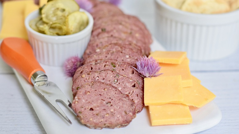 sliced venison sausage with cheese and pickles on charcuterie board