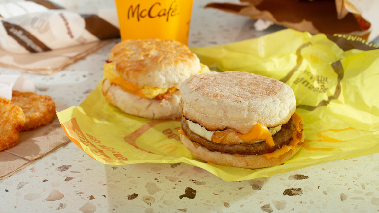 McDonald's McMuffins on paper with hash browns and coffee cup on table