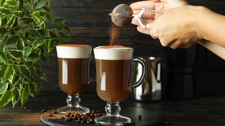 Hands dusting coffee cocktail with chocolate