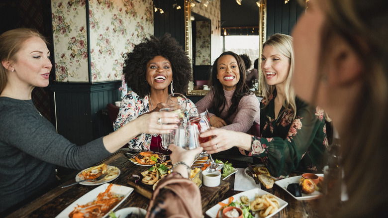 people at table in a restaurant, toasting with drinks