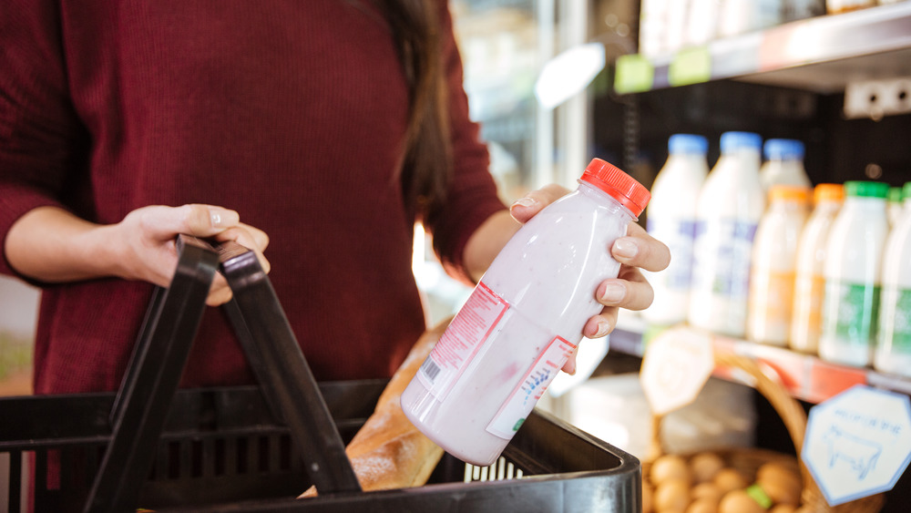 Woman carrying milk jug in grocery store