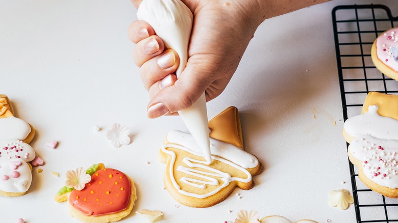 hand squeezing icing onto cookie