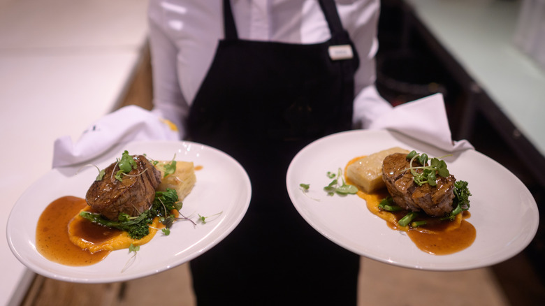 waiter holding steaks on plate