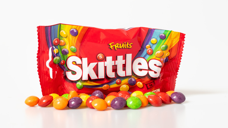 pack of skittles with handful of skittles candy in front of it