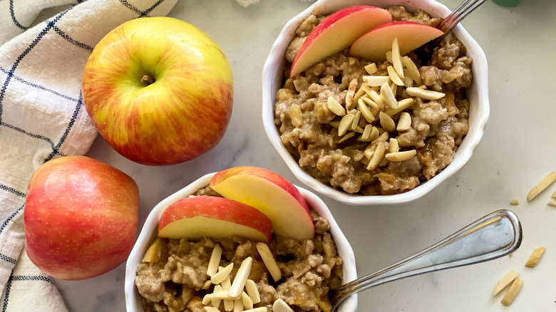 bowls of apple cinnamon oatmeal with whole and sliced apples