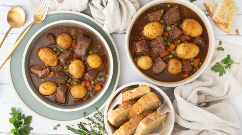 slow cooker beef stew in bowls with bread