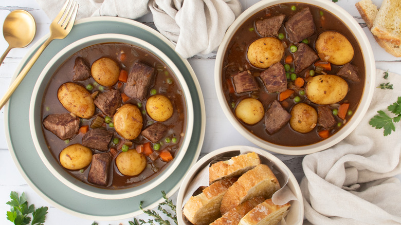 two bowls of slow cooker beef stew with bread