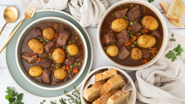 slow cooker beef stew in bowls with bread