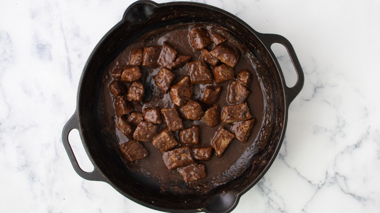 seared beef in skillet with gravy