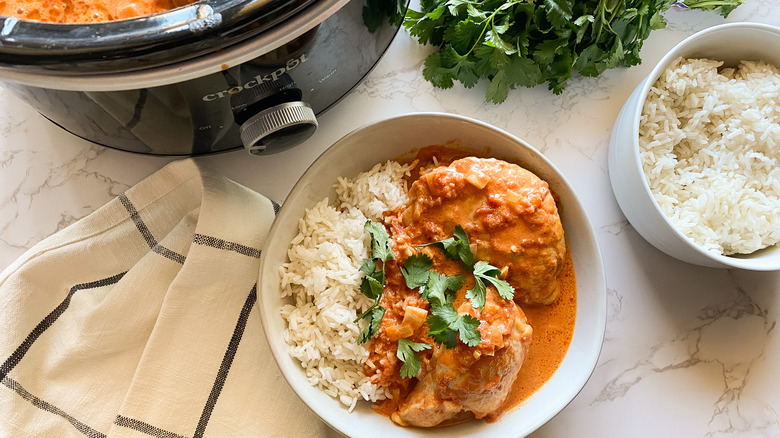 Slow Cooker Butter Chicken served in a bowl with rice and garnish