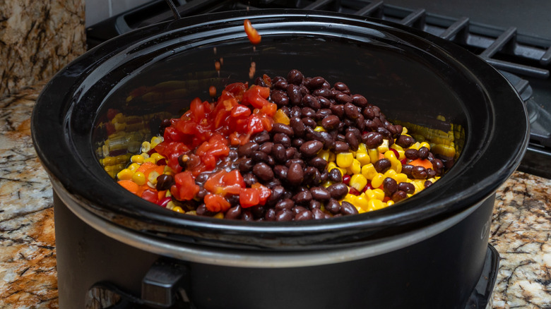 Someone pouring ingredients into a slow cooker.