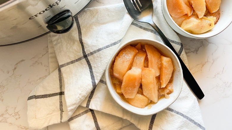 Finshed slow cooked stewed apples in bowls with napkin and spoon