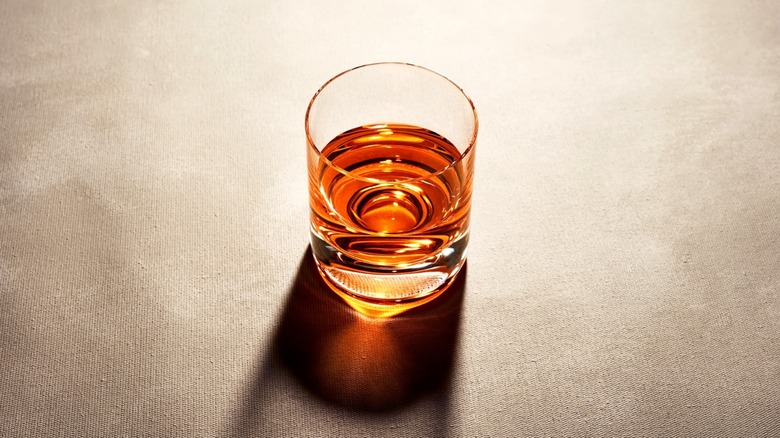A glass of straight whiskey on a gray table.
