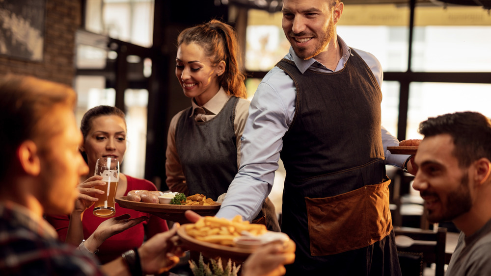 waiter bringing french fries to table