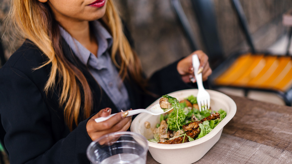 Woman at table eating a fast-food salad
