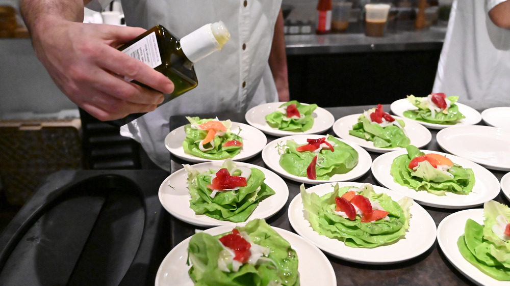 restaurant worker preparing a line of salads