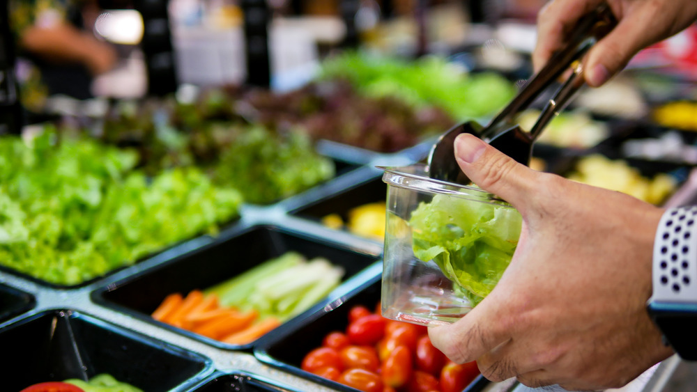 Man filling bowl at salad bar