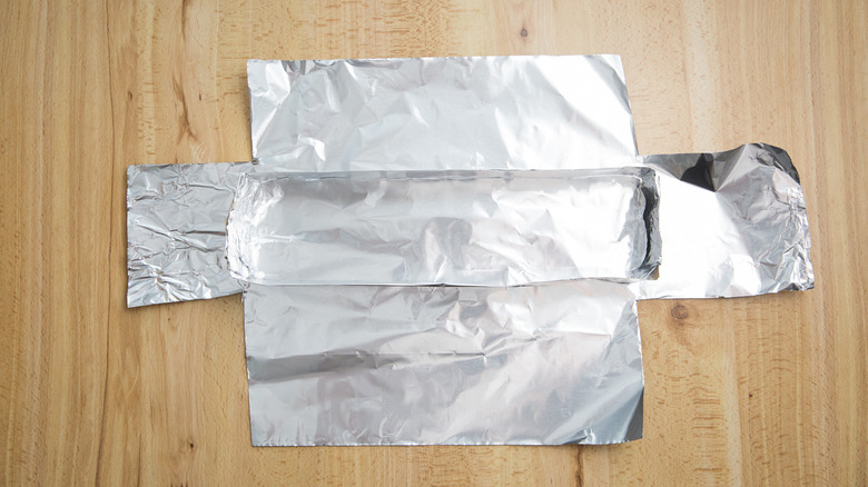 cut out sheet of aluminum foil under a makeshift rectangular aluminum foil on table