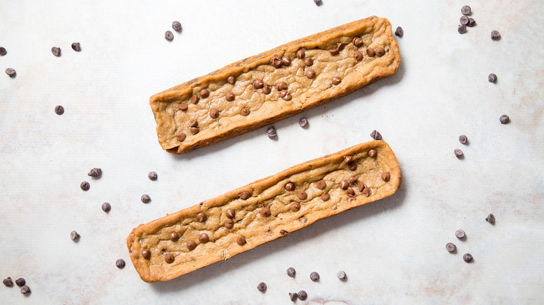 two copycat Subway footlong cookies on white background surrounded by chocolate chips