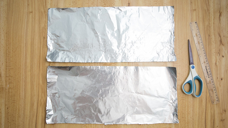 two aluminum foil sheets on table next to scissor and ruler